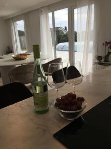 una mesa con dos copas de vino y un tazón de uvas en Stan- och strandnära poolvilla., en Halmstad