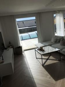 a living room with a couch and a table at Stan- och strandnära poolvilla. in Halmstad