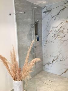 a shower with a glass door in a bathroom at Stan- och strandnära poolvilla. in Halmstad