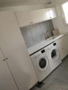 a white kitchen with a washing machine in it at Stan- och strandnära poolvilla. in Halmstad