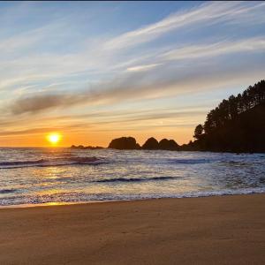 una playa con puesta de sol en el océano en Cabañas Pudá en Dichato