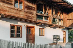 uma casa de madeira com um banco em frente em Bauernchalet elbacher gütel - Exklusives Ferienhaus am Starnberger See em Eurasburg