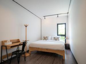 a bedroom with a bed and a desk and a window at Ombra House No. 21-24 in Chiang Mai