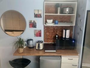 uma pequena cozinha com um balcão e um espelho em Lovely 1-Bed Studio Annex, Hampton, free parking em Hampton Hill