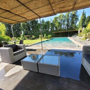 a swimming pool with chairs and a table and an umbrella at Le Mas des Mirabelles in Cabannes