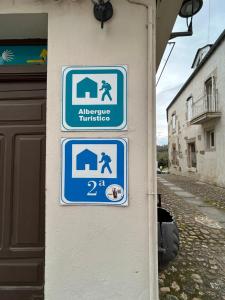 un grupo de señales en el lateral de un edificio en Albergue Mayor, en Sarria