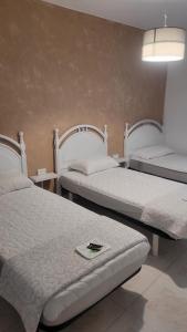 two beds in a hotel room with a cell phone on top at ALBERGUE de Caldas de Reis URRACA in Caldas de Reis