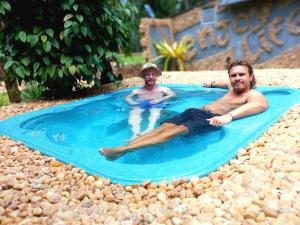 dos hombres tumbados en una piscina en un complejo en River View Safari Cottage., en Udawalawe