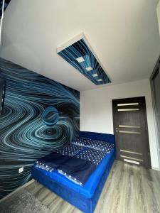 een kamer met een blauw bed en een schilderij aan de muur bij Gina Apartman in Debrecen