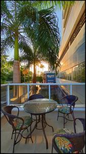 een patio met een tafel en stoelen en palmbomen bij Trip Hotel Ubá in Ubá