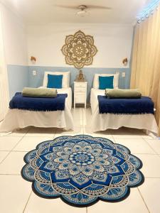 1 dormitorio con 2 camas y alfombra azul y blanca en Spazio Buzios Guesthouse, en Búzios