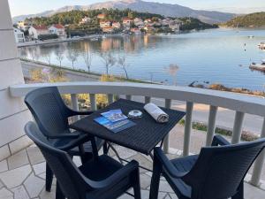a table and chairs on a balcony with a view of a lake at APARTMENTS Ana by the SEA in Lumbarda