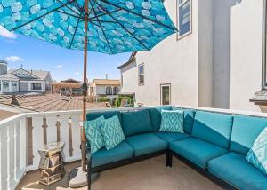 um sofá azul numa varanda com um guarda-chuva em Balboa Paradise - Renovated Coastal Haven em Newport Beach