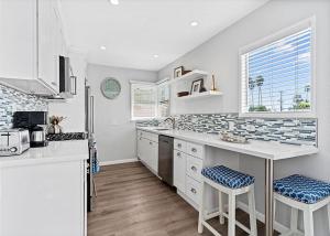 a white kitchen with a counter and stools in it at Balboa Paradise - Renovated Coastal Haven in Newport Beach