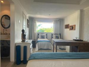 a bedroom with two beds and a table and a window at Spazio Buzios Guesthouse in Búzios