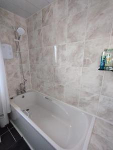 y baño con bañera blanca y paredes de azulejos. en Edinburgh Villa 3 bed Rooms House in Edinburgh - Private parking, en Edimburgo