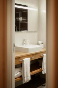 uma casa de banho com lavatório, espelho e toalhas em Hôtel Dali Val d'Europe em Chanteloup En Brie