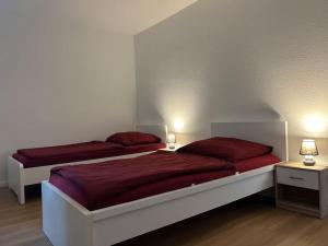 a bedroom with two beds with red sheets and lamps at Sonnenschein-Oase ,Apartment in Marl