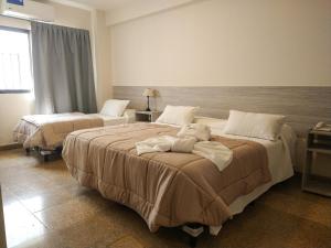 two beds in a hotel room with a teddy bear on them at GS Hotel in Salta