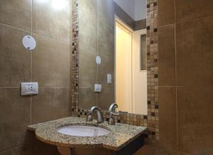 een badkamer met een wastafel en een spiegel bij GS Hotel in Salta