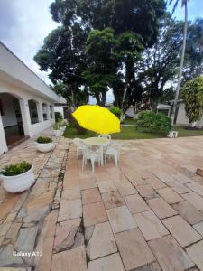 un patio con una mesa y una sombrilla amarilla en Elysian Place en Atibaia