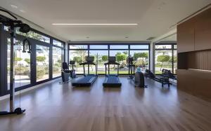 a gym with treadmills and ellipticals in a room with windows at Thalassa Beach Resort in Vokolidha