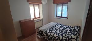 ein Schlafzimmer mit einem Bett, einer Kommode und zwei Fenstern in der Unterkunft Il Rifugio in Tarvis