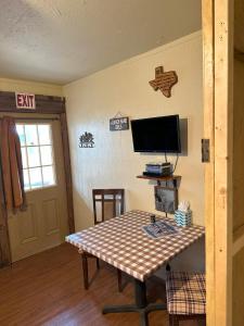 Habitación con mesa y TV en la pared. en Acorn Hideaways Canton Old Western Ranch Hands' Suite en Canton