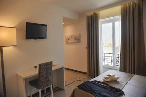 um quarto de hotel com uma cama, uma secretária e uma televisão em Hotel Villa Centa em Varazze