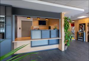 an office lobby with a reception desk and a plant at B&B HOTEL CHARTRES Oceane in Chartres