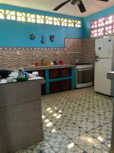 a kitchen with blue walls and a white refrigerator at La ballena cosmic las peñitas in Las Peñitas