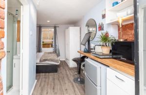 a tiny house with a desk and a bedroom at Lovely 1-Bed Studio Annex, Hampton, free parking in Hampton Hill