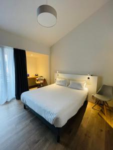 - une chambre avec un grand lit blanc et une chaise dans l'établissement Hotel Restaurant Santiago, à Hendaye