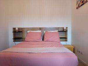 1 dormitorio con 1 cama con sábanas y almohadas rosas en COCOONING HOUSE B222 Suite ZEN & PEACEFUL AEROPORT PARIS ROISSY CDG - PARC ASTERIX- STADE DE FRANCE en Survilliers