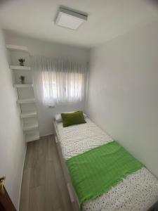 um pequeno quarto com uma cama com uma almofada verde em J&V Apartamento em Ronda