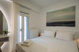 a bedroom with a white bed with a painting on the wall at ELiXiR 2 Luxury apartments in Agios Nikolaos