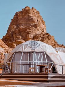 a large dome tent with two chairs in front of a mountain at Rum Crystal Luxury Camp in Wadi Rum