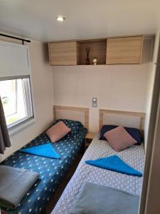 Duas camas num pequeno quarto com almofadas azuis em Camping Mar Estang em Canet-en-Roussillon