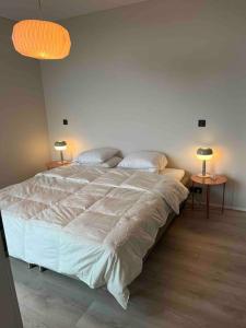 a large bed in a bedroom with two tables at New apartment in the capital region in Garðabær