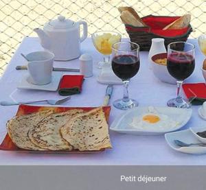 un tavolo con due bicchieri di vino e un piatto di cibo di B and B Pieds dans l'eau a Poponguine
