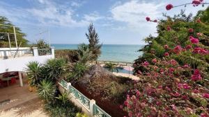 una vista sull'oceano da una casa con fiori di B and B Pieds dans l'eau a Poponguine