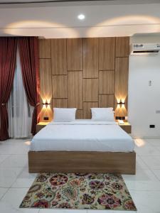 a bedroom with a large bed with two tables and a rug at Samuel Court in Abuja