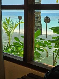 a window with a view of the beach and the ocean at Lagoon View Maldives in Bodufolhudhoo