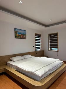 ein Schlafzimmer mit einem großen Bett mit einer hölzernen Plattform in der Unterkunft La foret Vân Hoà villa 2 in Hanoi