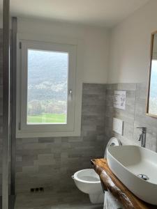 baño con lavabo y aseo y ventana en ALTRAVISTA TARZO en Revine Lago