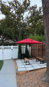 a picnic table with a red umbrella and two benches at One room with one queen bed studio to rent in Palo Alto