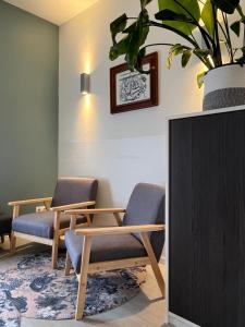 een wachtkamer met twee stoelen en een tafel en een potplant bij Bed & Brasserie Het Kosthuys in Sint Maartensdijk