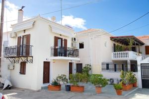 a white house with potted plants in front of it at Old Harbour Aroura 2BR Home in Spetses