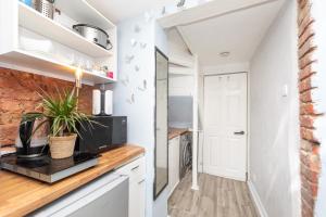 uma cozinha com armários brancos e uma parede de tijolos em Lovely 1-Bed Studio Annex, Hampton, free parking em Hampton Hill