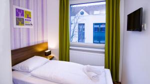 ein Schlafzimmer mit einem weißen Bett und einem Fenster in der Unterkunft Hirsch Hotel Hanau in Hanau am Main
